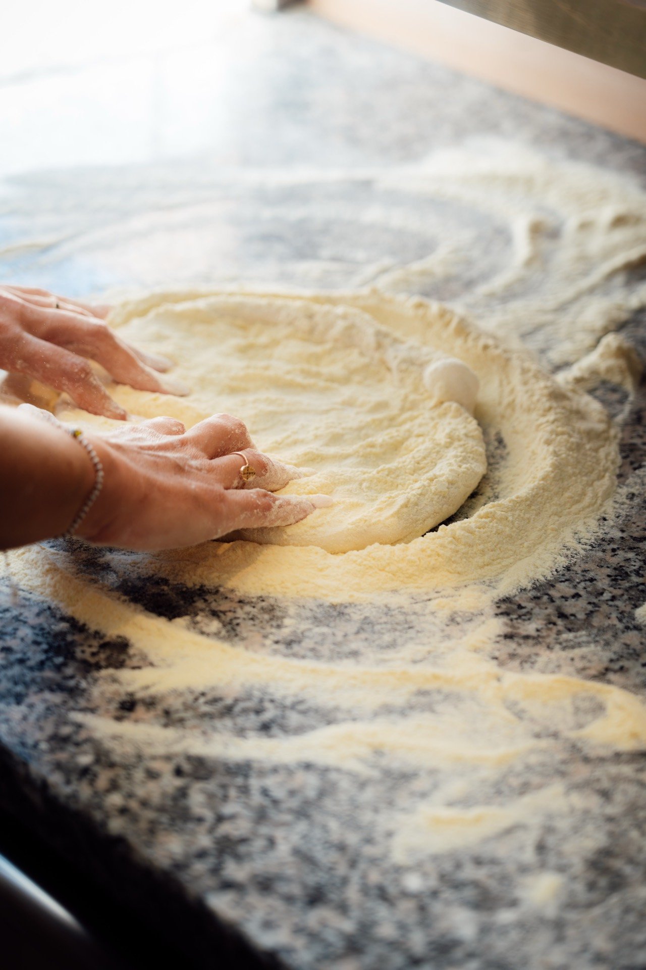 Une pizzaiola façonne la pâte à la main sur le plan de travail.